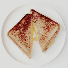 two grilled cheese sandwiches on a white plate with syrup drizzled over them