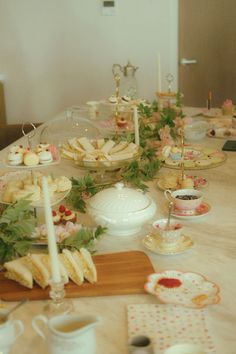 a table is set up with tea cups, plates and desserts on the table