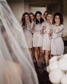 a group of women standing next to each other in front of a wedding dress mirror