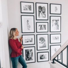 a woman standing in front of a wall with pictures on it