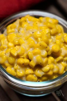 a glass bowl filled with macaroni and cheese on top of a wooden table