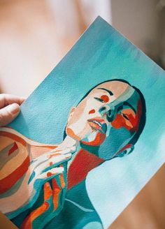 a person holding up a piece of art with a woman's face painted on it