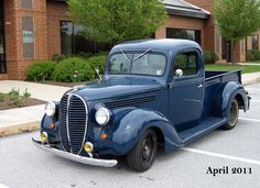 an old blue truck parked in a parking lot