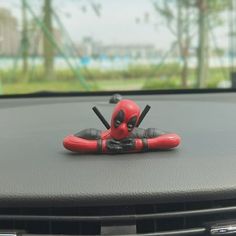 a deadpool toy is sitting on the dashboard of a car