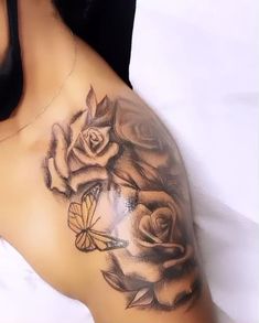 a woman with a butterfly and roses tattoo on her arm, laying down next to a white sheet