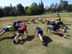 a group of people doing push ups in the grass