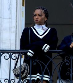 two women standing next to each other on a balcony looking at something in the distance