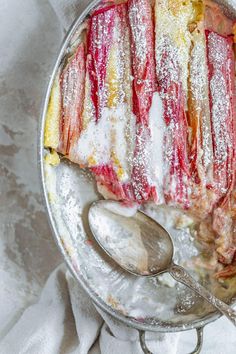 a metal pan filled with food covered in powdered sugar next to two spoons