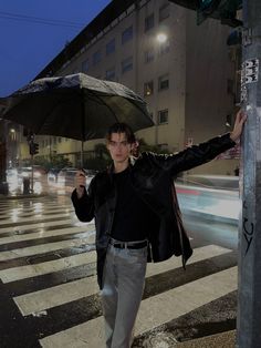 a man holding an umbrella while crossing the street at night in front of a building