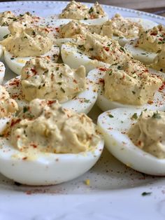 deviled eggs with mayonnaise and seasoning sit on a white platter