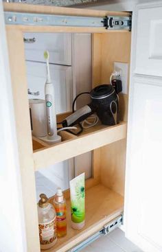 an open cabinet with toothbrushes, hairdryer and other items