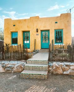 a yellow house with green doors and steps leading up to it