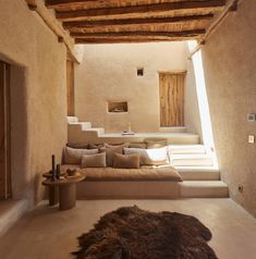 a living room filled with lots of furniture next to a stone wall and wooden beams