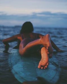 a person laying on top of a surfboard in the ocean with their feet propped up