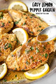 lemon pepper chicken in a skillet with sliced lemons and parsley