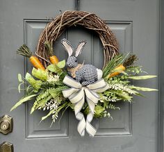 a wreath with an easter bunny sitting on it's front door decorated with greenery and carrots