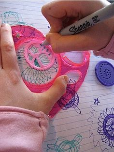 a child's hand writing on a piece of paper next to scissors and buttons