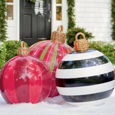 three christmas ornaments sitting in the snow next to a black and white striped ornament