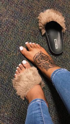 a woman's feet with a tattoo on her left foot and a pair of slippers