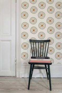 a wooden chair sitting in front of a wall with a pattern on the wall behind it