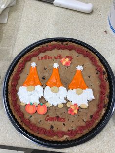 there is a cake decorated with three gnomes on it's face and two pumpkins in the middle