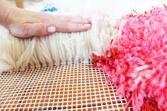 a person is touching the end of a pink and white sheep's wool pile