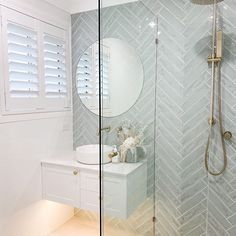 a bathroom with a walk in shower next to a white sink and mirror on the wall