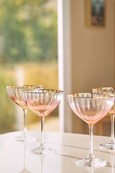 three wine glasses sitting on top of a table next to each other with gold rims