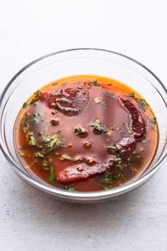 a glass bowl filled with soup on top of a white counter next to a spoon