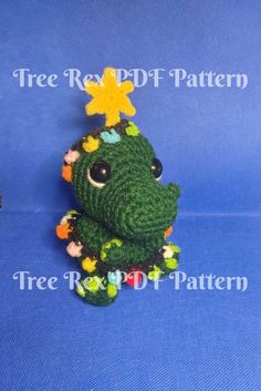 a small crocheted frog with a star on its head sitting in front of a blue background