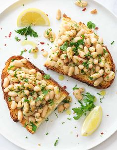 two pieces of toast topped with beans and parsley on top of a white plate