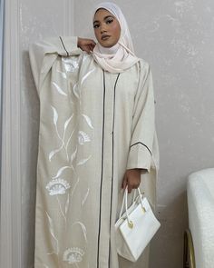 *SUMMER 2024 COLLECTION* This gorgeous Beige butterfly-cut abaya made of Premium Linen Blend is perfect for this summer. It features handmade white embroidery, black piping that gives a beautiful frame to the abaya, buttons for closure and complimented by our Signature Lazer (ليزر) Chiffon. Our Summer Collection comes limited.  The sizes refer to the length of the abaya (in inches) from shoulder down.  The model is 5ft4 tall and wears size 54.  Abaya Material: Premium Linen Blend (not Organic) S White Long Sleeve Abaya With Floral Embroidery, Spring Long Abaya With Floral Embroidery, Spring Abaya With Floral Embroidery, Spring Floral Embroidered Long Abaya, Spring Floral Embroidered Abaya, White Embroidered Abaya For Eid, Spring Floral Embroidered Maxi Abaya, Spring Floral Embroidered Maxi Length Abaya, White Spring Abaya