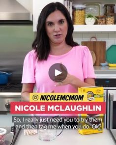 a woman in a pink shirt is holding up a box of nicole mclaughlin