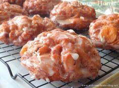 several donuts with icing and nuts are on a cooling rack, ready to be eaten