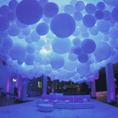 a room filled with lots of white balloons hanging from the ceiling and couches in front of it