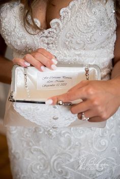 a woman in a wedding dress is holding a white purse with her name on it