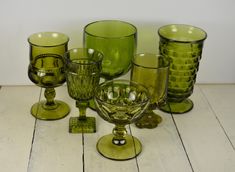 a group of green glassware sitting on top of a wooden table next to each other