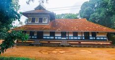 a white and blue building sitting on top of a dirt field next to green trees