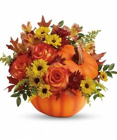 an orange pumpkin filled with flowers and leaves