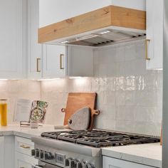 a stove top oven sitting inside of a kitchen next to white cabinets and counter tops