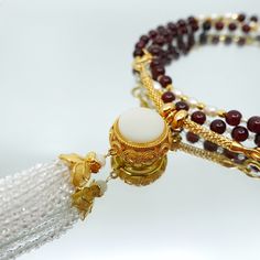 This necklace features 81 primary gemstones made of garnet, as well as spacer gemstones made of fresh water pearls and faceted zircon. The number 9 is considered significant in ancient Chinese culture, and the necklace's design incorporates this belief with its 81 gemstones. The necklace can be worn as a traditional necklace or as a glasses chain. The pendant features a white jade gemstone with a filigree design and faceted zircon tassel. The pendant can be detached from the necklace and replace Traditional Necklace, Asian Jewelry, Jade Gemstone, Number 9, Garnet Necklace, Fresh Water Pearls, White Jade, Filigree Design, Glasses Chain