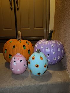 three painted pumpkins sitting on the front steps