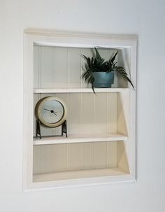 a shelf with a clock, plant and potted plants on it's sides