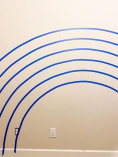 a white wall with blue lines painted on it and an electrical outlet in the middle