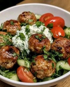 a white bowl filled with meatballs, cucumbers, tomatoes and lettuce