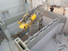 a construction site with concrete walls and pipes in the foreground, while a man is standing on the other side of the building