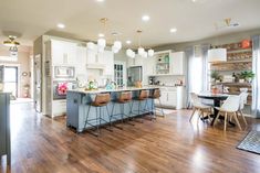 a large kitchen with an island and bar stools in the center, surrounded by white cabinets