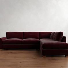 a red couch sitting on top of a hard wood floor next to a white wall