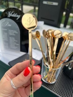 a woman holding up a gold colored spoon in front of a table with silverware on it