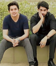 two young men sitting on a cement bench next to each other